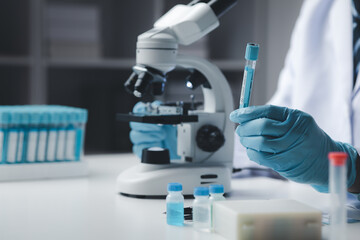 Lab assistant, medical scientist, chemistry researcher holds a glass tube through a chemical test tube, does a chemical experiment and examines a patient's sample. Medicine and research concept.