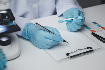 Lab assistant, medical scientist, chemistry researcher holds a glass tube through a chemical test tube, does a chemical experiment and examines a patient's sample. Medicine and research concept.