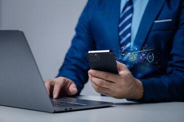 Businessman holding smartphone with business hologram, using technology to analyze and plan business, marketing, planning solutions in business using modern technology.