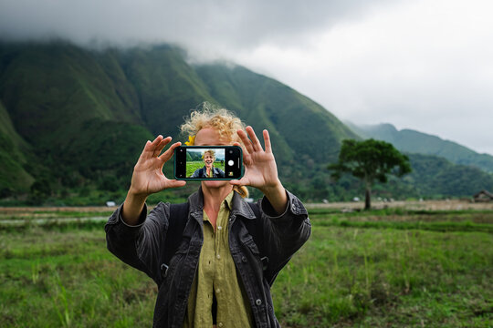 A young girl traveler makes a selfie on a mobile phone against the backdrop of mountains.
