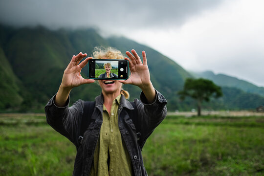 A young girl traveler makes a selfie on a mobile phone against the backdrop of mountains.