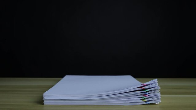 A pile of paper documents, clippings, falling down, on a wooden table, organizing documents &ndash; 4K Stop Motion, Stack Files Overload.