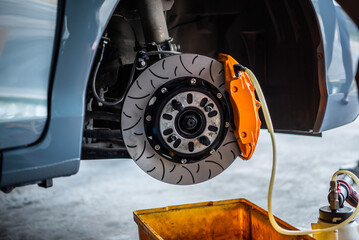 Car mechanic or serviceman disassembly and checking a disc brake and asbestos brake pads for fix and repair problem at car garage or repair shop