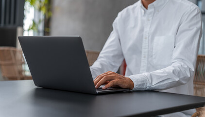 Businesman typing on laptop keyboard, wearing white shirt