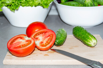 Sliced red tomatoes and green cucumbers are cooked on a wooden b