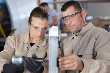 male and female workers using air tool in workshop