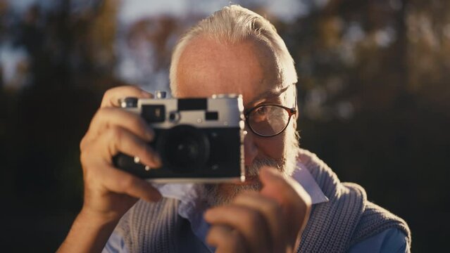 Curious senior man holding vintage camera, photography as a hobby, lifestyle
