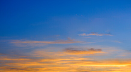 Dramatic Dusk Sky Background in the Evening with majestic yellow sunlight and clouds on blue Twilight after sundown