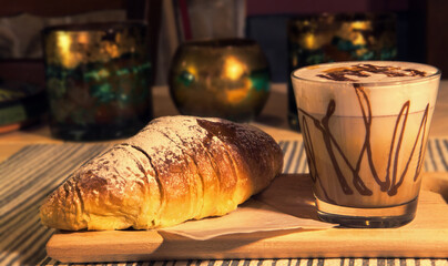 Typical Italian breakfast, a steaming and decorated cappuccino and a freshly baked croissant