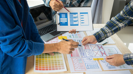 Close-up ux developers and ui designers use augmented reality to brainstorm on mobile app interface wireframe designs on modern office desks. Creative digital development office