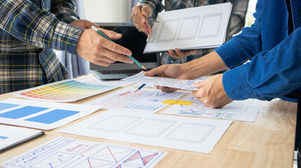 Close-up ux developers and ui designers use augmented reality to brainstorm on mobile app interface wireframe designs on modern office desks. Creative digital development office