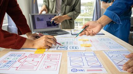 Close-up ux developers and ui designers use augmented reality to brainstorm on mobile app interface wireframe designs on modern office desks. Creative digital development office