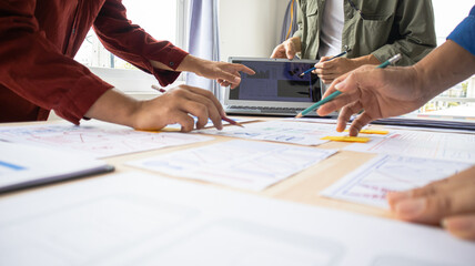 Close-up ux developers and ui designers use augmented reality to brainstorm on mobile app interface wireframe designs on modern office desks. Creative digital development office