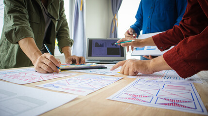 Close-up ux developers and ui designers use augmented reality to brainstorm on mobile app interface wireframe designs on modern office desks. Creative digital development office