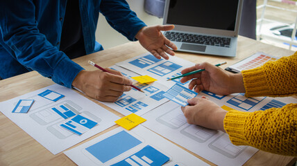 Close-up ux developers and ui designers use augmented reality to brainstorm on mobile app interface wireframe designs on modern office desks. Creative digital development office