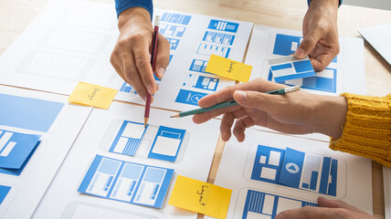 Close-up ux developers and ui designers use augmented reality to brainstorm on mobile app interface wireframe designs on modern office desks. Creative digital development office