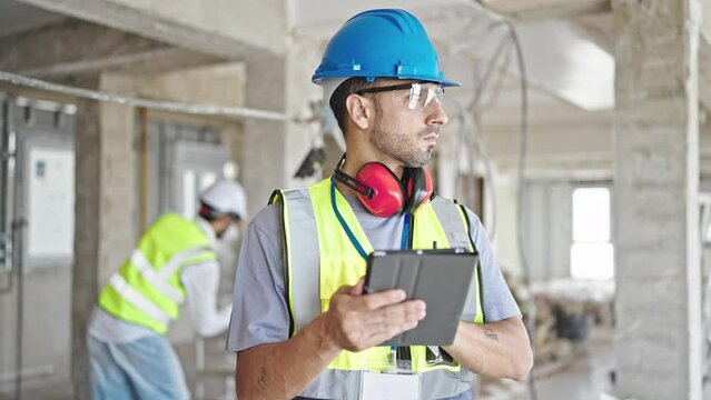 Two men builders using touchpad at construction site