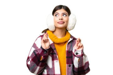 Young Russian woman wearing winter muffs over isolated chroma key background with fingers crossing