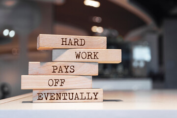 Wooden blocks with words 'Hard work pays off eventually'.