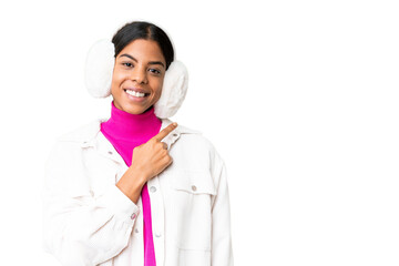 Young African American woman wearing winter muffs over isolated chroma key background pointing to...