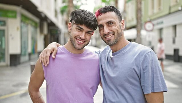 Two men couple smiling confident hugging each other kissing at street