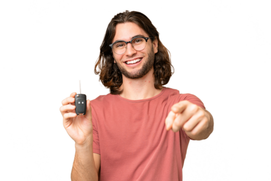 Young handsome man holding car keys over isolated background points finger at you with a confident expression