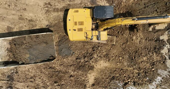 excavating soil into a dump truck to build a pond for store water for use in the dry season for agriculture 4k video top view from drone,