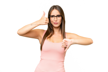 Young pretty caucasian woman over isolated background making good-bad sign. Undecided between yes or not