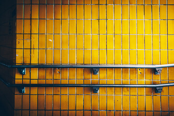 Rampe et mur carrelé en jaune dans les sous terrain du métro