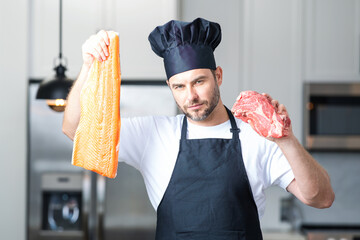 Middle aged man cooking fish and meat, salmon and beef in kitchen. Man on kitchen with fish and meat, salmon and beef.