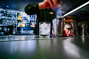 man bartender hand making negroni cocktail. Negroni classic cocktail and gin short drink with sweet vermouth, red bitter liqueur