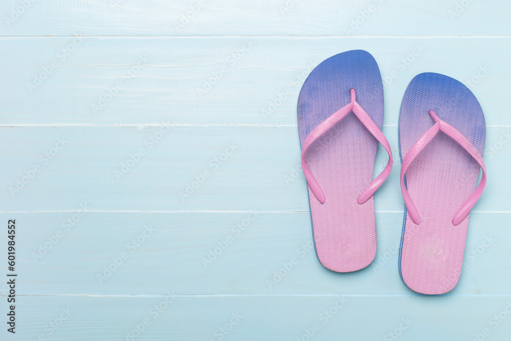 Wall mural Bright flip flops on wooden background, top view