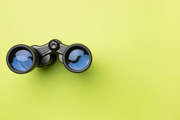 Black binoculars on color background. Top view