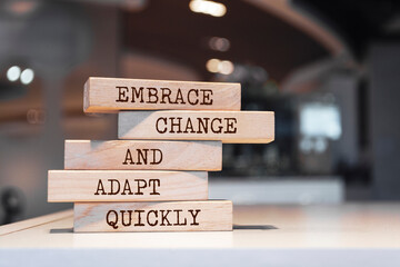 Wooden blocks with words 'Embrace change and adapt quickly'.