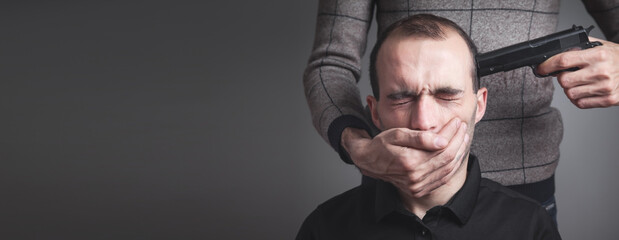 Person with a handgun aiming on a man head.
