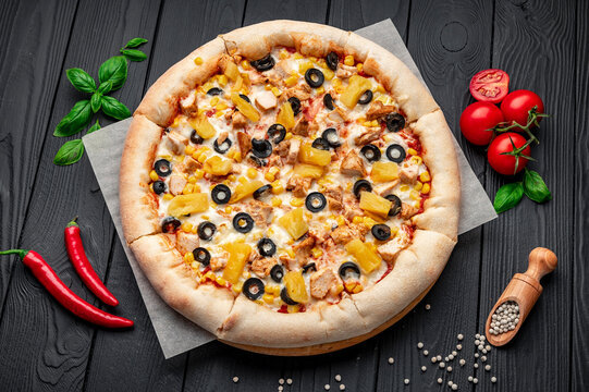 Delicious pizza with chicken meat, pineapple, corn and olives