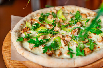 Delicious pizza with grilled chicken, avocado, and arugula.