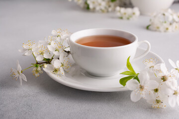A cup of tea on the table with spring cherry blossoming branches