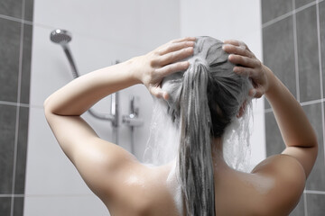 Fototapeta premium Woman washing hair with shampoo and shower in the bathroom