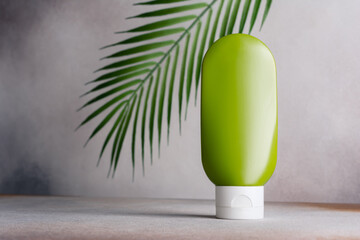 Green blank packaging cosmetic container with palm leaves on background