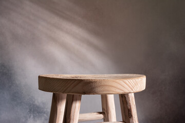 Wooden stool and shadows of palm leaves on background.