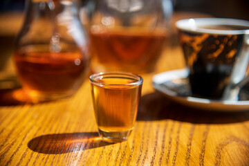 A glass of old brandy on the table...blurred background...morning drink brandy and coffe..."rakija"...old "sljivovica"...