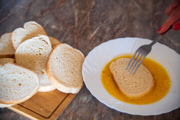 She prepares bread with eggs in the kitchen...