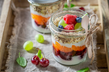 Delicious and homemade granola in jar with yoghurt.
