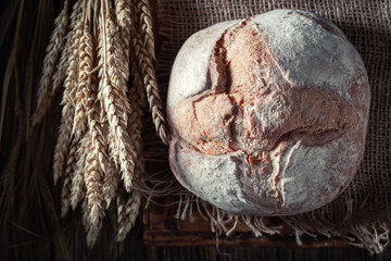 Fresh and rustic loaf of bread with grain and ears.
