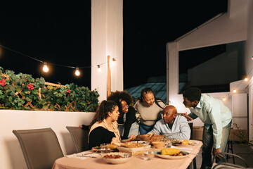 Happy African family dining together on house patio