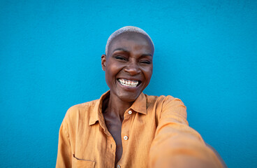 Happy African woman having fun taking selfie with smartphone camera outdoor