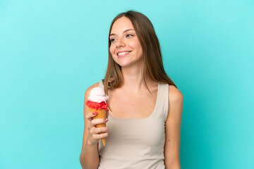 Young Lithuanian woman with cornet ice cream isolated on blue background looking to the side and smiling