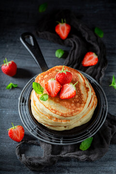 Yummy and fresh american pancakes with strawberries and sugar.