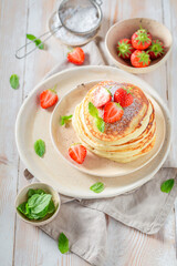 Delicious and hot american pancakes with powdered sugar and fruits.